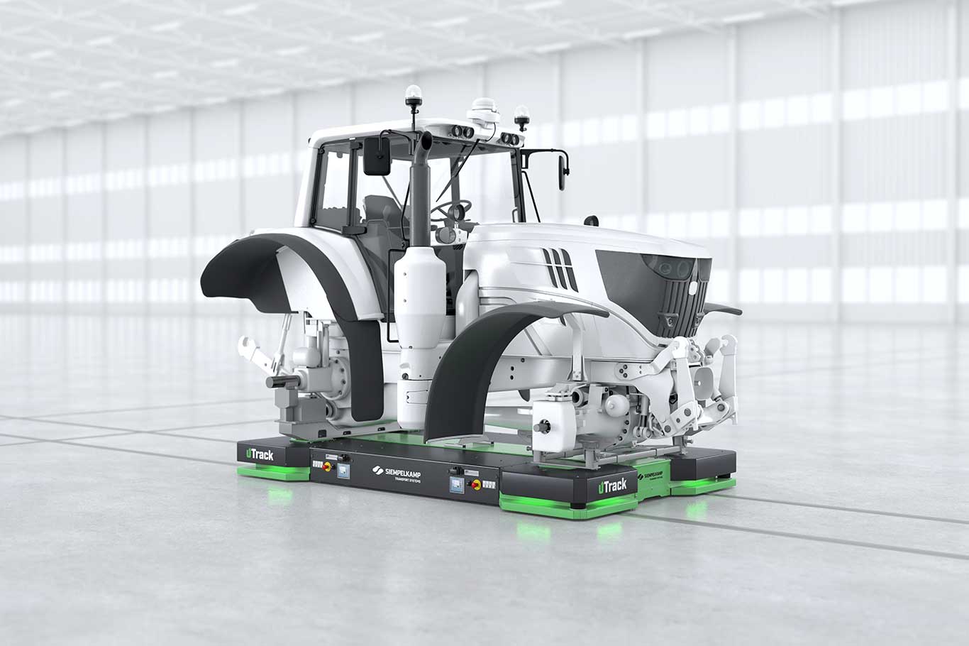 A green tractor is positioned on a platform inside a large, well-lit warehouse.